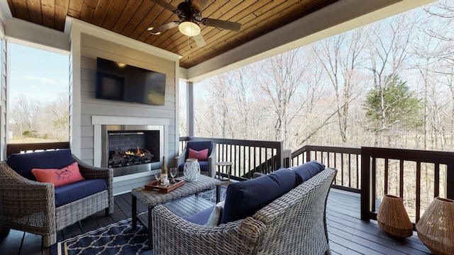 wooden terrace with an outdoor living space with a fireplace and ceiling fan