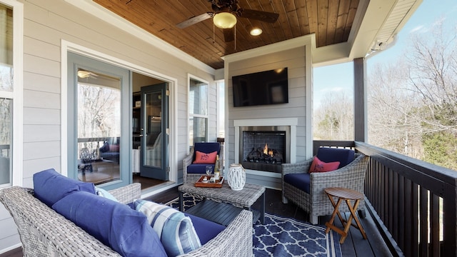 wooden terrace featuring ceiling fan and an outdoor living space with a fireplace