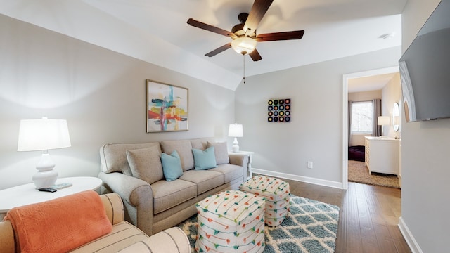 living room featuring dark wood-type flooring, ceiling fan, and vaulted ceiling