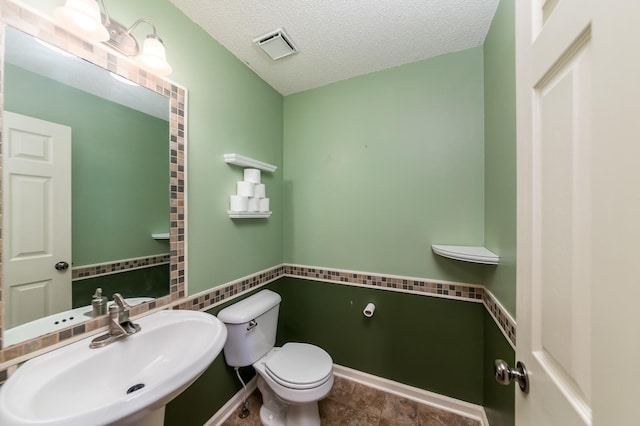 bathroom with a textured ceiling, sink, and toilet