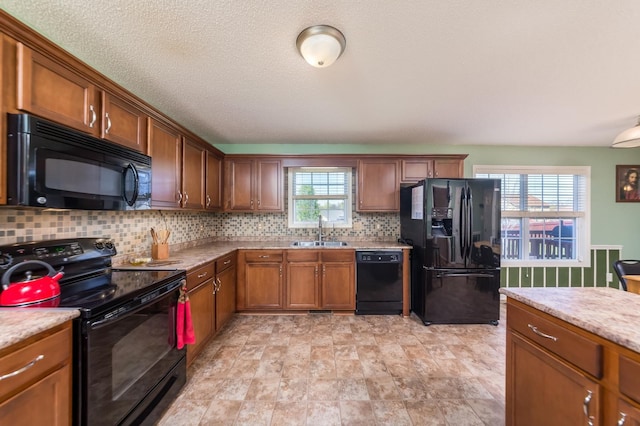 kitchen with black appliances, light stone countertops, a wealth of natural light, and sink