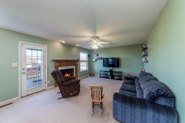 carpeted living room featuring ceiling fan and a textured ceiling