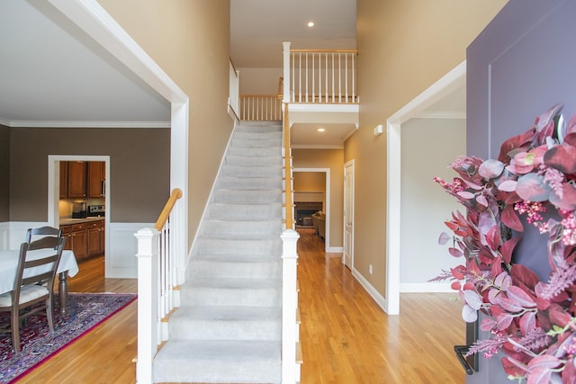 staircase featuring hardwood / wood-style floors, a towering ceiling, and ornamental molding