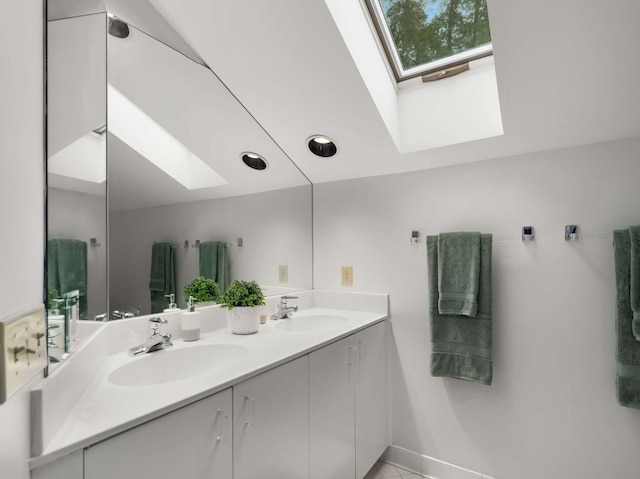 bathroom featuring vaulted ceiling with skylight and vanity