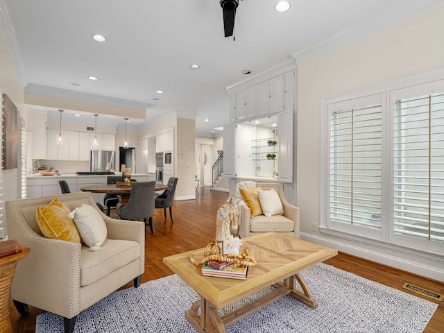 living room with light hardwood / wood-style floors, ceiling fan, and ornamental molding