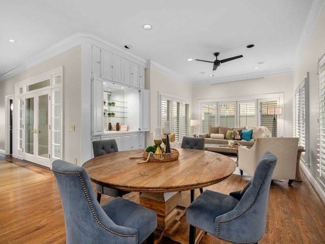 dining space with wood-type flooring, ceiling fan, and crown molding