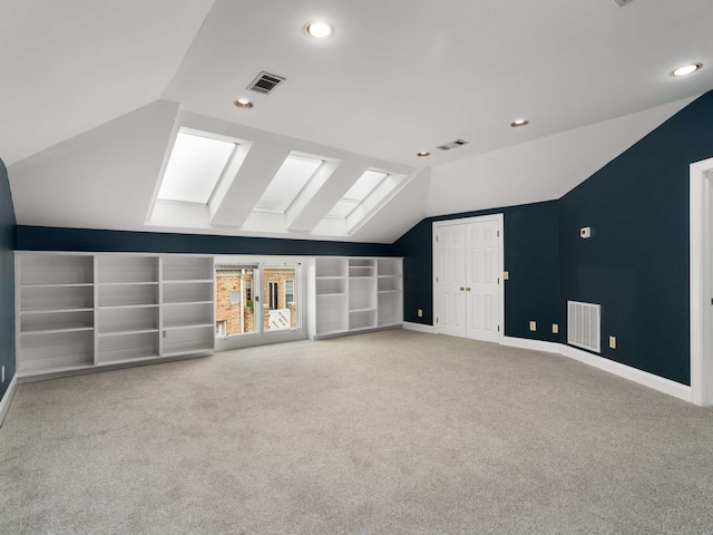 additional living space with light colored carpet and vaulted ceiling with skylight