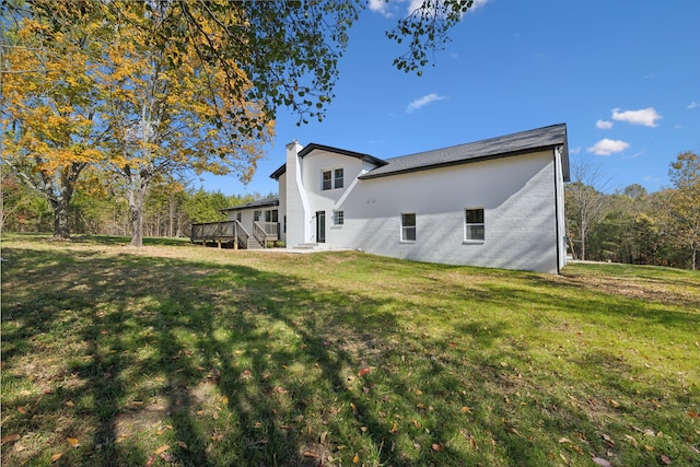 rear view of property featuring a wooden deck and a lawn