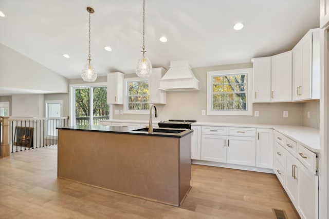 kitchen featuring white cabinetry, light hardwood / wood-style floors, and premium range hood