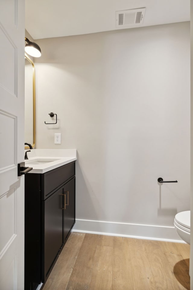 bathroom with hardwood / wood-style floors, vanity, and toilet