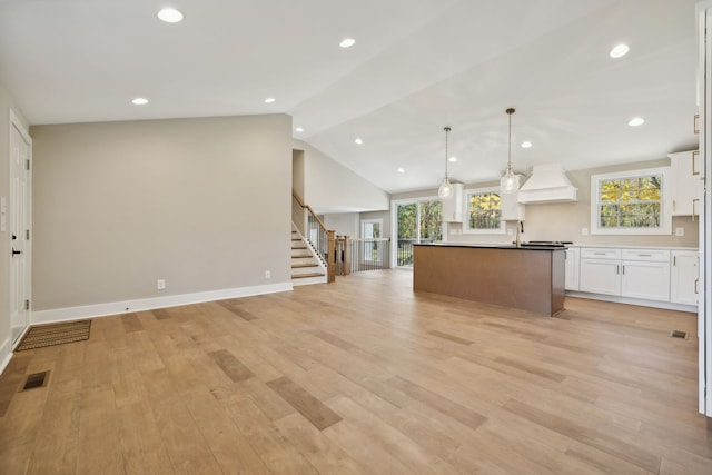 kitchen featuring white cabinets, a wealth of natural light, custom range hood, and pendant lighting