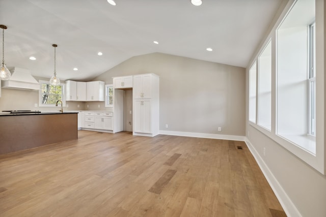 kitchen featuring white cabinetry, custom range hood, light hardwood / wood-style flooring, and hanging light fixtures