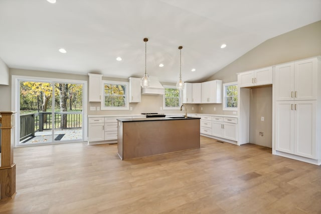 kitchen with light hardwood / wood-style floors, white cabinetry, sink, a kitchen island, and pendant lighting