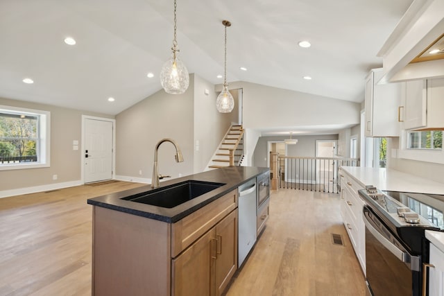 kitchen with appliances with stainless steel finishes, sink, an island with sink, white cabinets, and lofted ceiling