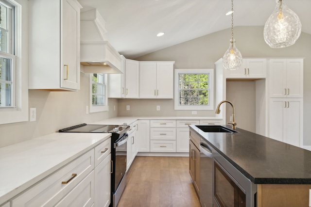 kitchen with stainless steel appliances, a center island with sink, sink, lofted ceiling, and white cabinets