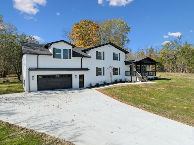 view of front of house with a front yard, covered porch, and a garage