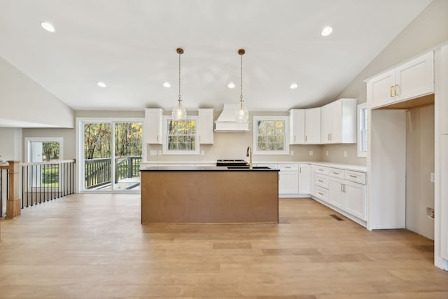 kitchen featuring white cabinets, vaulted ceiling, premium range hood, and plenty of natural light