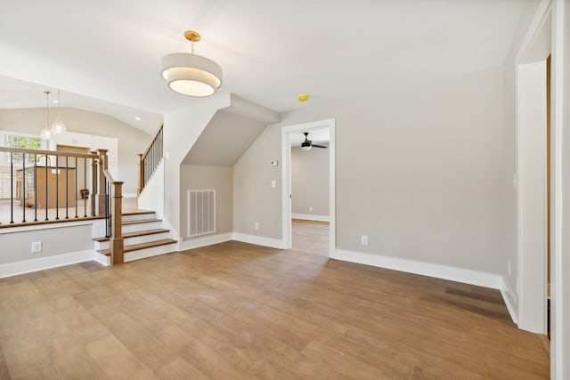 unfurnished living room featuring ceiling fan with notable chandelier, wood-type flooring, and lofted ceiling