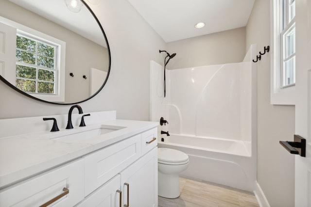 full bathroom featuring toilet, wood-type flooring, vanity, and  shower combination