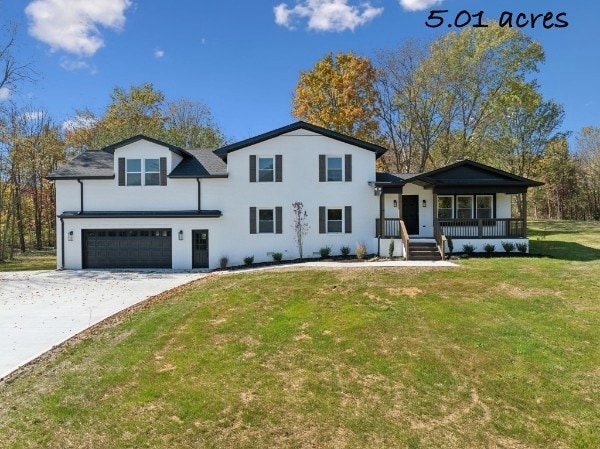 view of front of house featuring covered porch, a garage, and a front yard