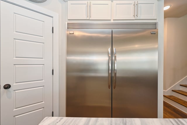 kitchen featuring white cabinets, hardwood / wood-style flooring, and built in refrigerator