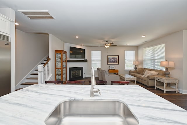 kitchen with sink, light stone counters, ceiling fan, dark hardwood / wood-style floors, and stainless steel built in refrigerator