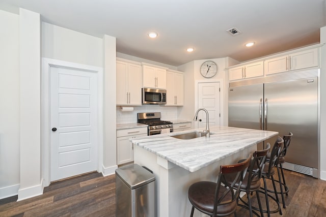 kitchen featuring a kitchen island with sink, appliances with stainless steel finishes, sink, and white cabinets