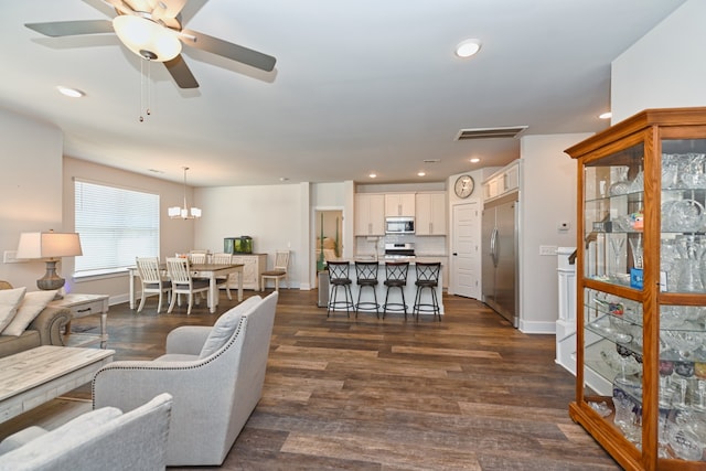 living room featuring ceiling fan with notable chandelier and dark hardwood / wood-style floors