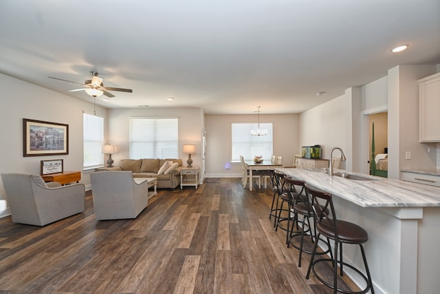 living room featuring dark wood-type flooring, sink, and ceiling fan