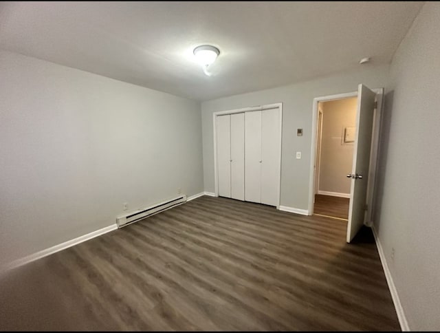 unfurnished bedroom featuring a closet, dark hardwood / wood-style flooring, and a baseboard heating unit