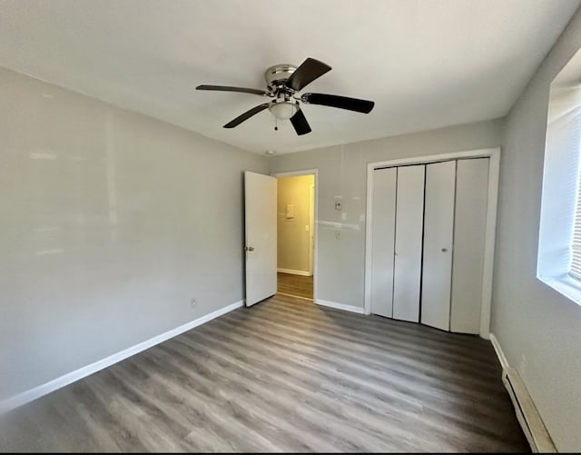 unfurnished bedroom with ceiling fan, a closet, wood-type flooring, and a baseboard radiator