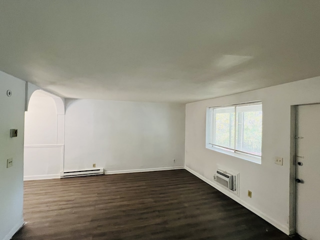 empty room featuring dark hardwood / wood-style flooring, a wall mounted AC, and a baseboard heating unit