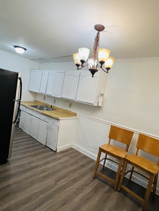 kitchen featuring black fridge, white cabinets, hanging light fixtures, and dark hardwood / wood-style floors