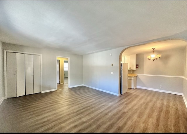 unfurnished living room featuring wood-type flooring and a notable chandelier