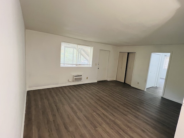 unfurnished room with dark hardwood / wood-style flooring and an AC wall unit