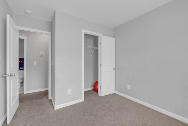 unfurnished bedroom featuring light colored carpet and a closet