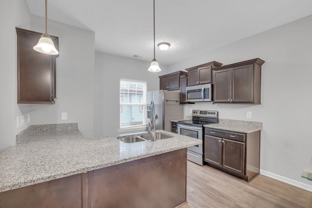 kitchen featuring kitchen peninsula, dark brown cabinets, stainless steel appliances, pendant lighting, and light hardwood / wood-style flooring