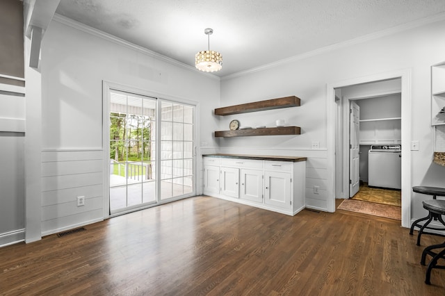 unfurnished dining area with dark hardwood / wood-style flooring, a textured ceiling, and ornamental molding