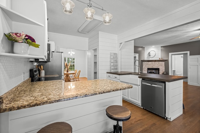 kitchen featuring stainless steel appliances, a kitchen breakfast bar, decorative light fixtures, white cabinets, and dark wood-type flooring