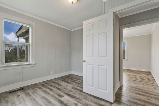 empty room with wood-type flooring and ornamental molding