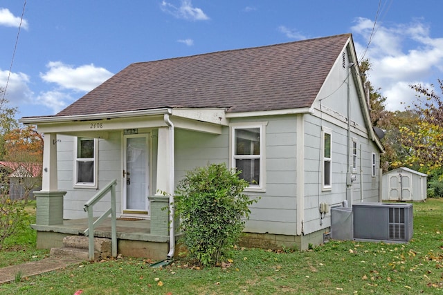 view of front of property featuring a front lawn, a shed, and central air condition unit