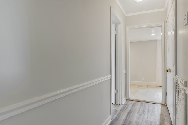 corridor with light hardwood / wood-style floors and crown molding