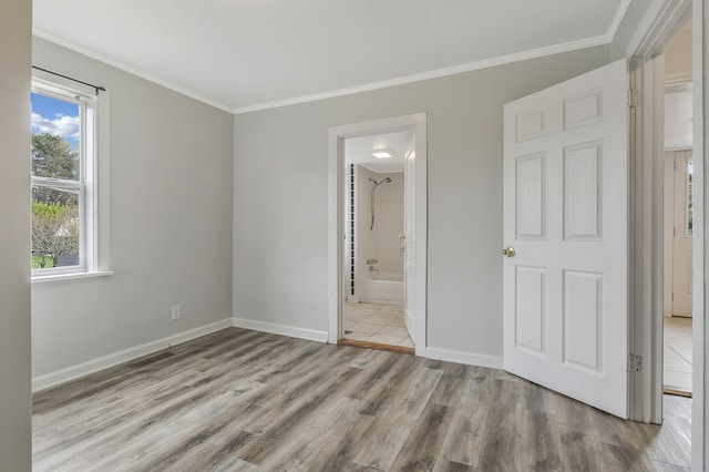 unfurnished bedroom featuring connected bathroom, light wood-type flooring, and crown molding