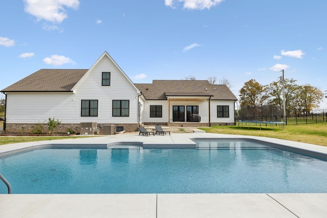 view of pool featuring a yard, a patio, central AC, and a trampoline