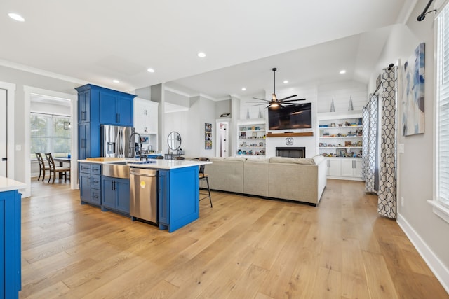 kitchen featuring blue cabinetry, a kitchen breakfast bar, appliances with stainless steel finishes, and an island with sink