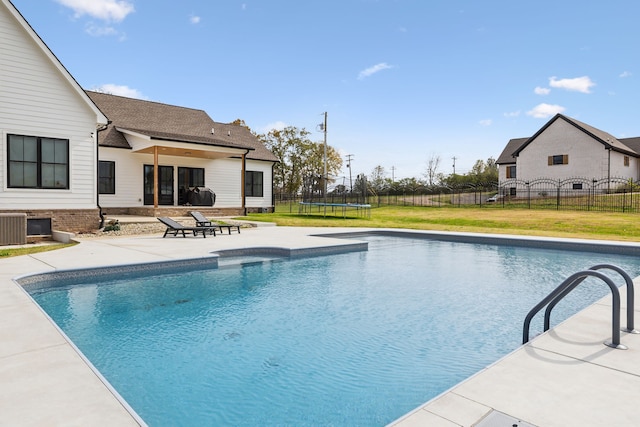 view of pool with central air condition unit, a patio area, a yard, and a trampoline