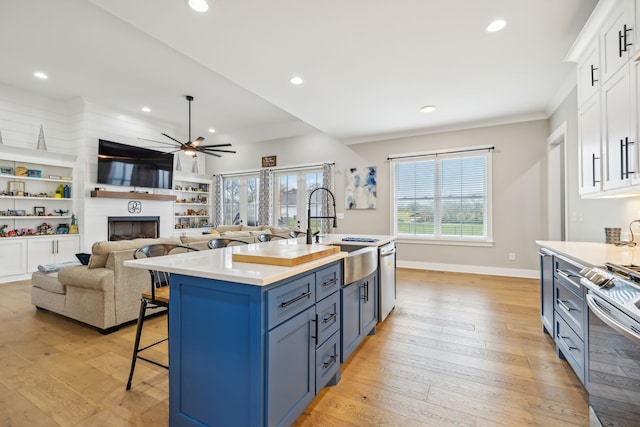 kitchen featuring white cabinetry, a kitchen island with sink, light hardwood / wood-style floors, and blue cabinets