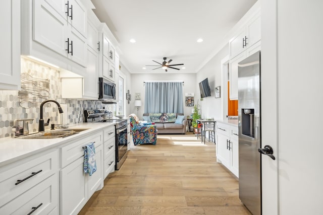 kitchen featuring stainless steel appliances, sink, backsplash, white cabinetry, and light hardwood / wood-style flooring