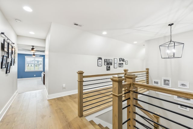 corridor with lofted ceiling, an inviting chandelier, and light hardwood / wood-style floors