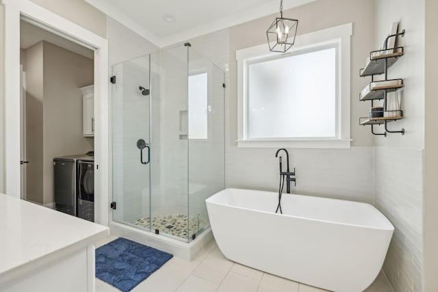 bathroom with tile walls, separate washer and dryer, tile patterned flooring, and shower with separate bathtub